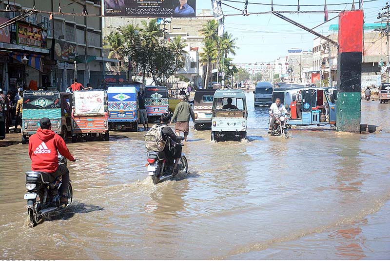 Motorcycles and rickshaw passing through rain water accumulated on the Korangi Road after rain that experienced the Provincial Capital.
