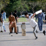 Youngsters playing cricket on road at Frere Hall