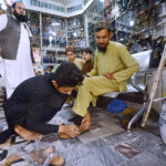 Customer selecting and purchasing traditional shoes (Peshawari Chappal) from a shopkeeper in preparation connection with upcoming Eid-ul-Fitar