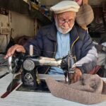 An elder tailor busy sewing traditional cap at his workplace in the City