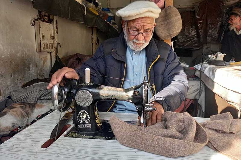 An elder tailor busy sewing traditional cap at his workplace in the City