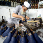 Cobblers preparing traditional shoes (Peshawari Chappal) at his workplace at Namak Mandi