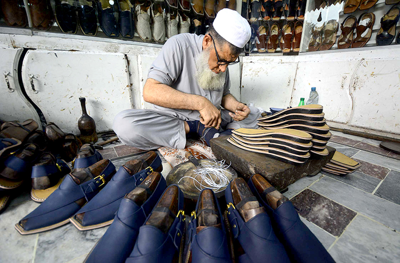 Cobblers preparing traditional shoes (Peshawari Chappal) at his workplace at Namak Mandi