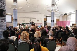 Ambassador Masood Khan addressing a jam-packed hall with a large number of women participants during an event held at the Embassy of Pakistan celebrating Pakistan's cultural treasures and the stunning landscape featuring traditional apparel, delicious cuisine, and exquisite artwork