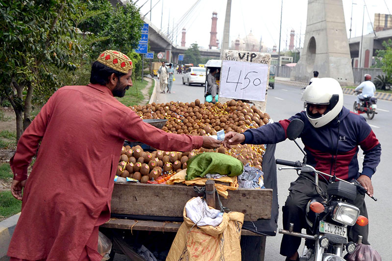 A customer is buying Kiwi fruit from a vendor on Ravi Road.
