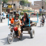 A family is traveling on a motor-cart driven by a boy