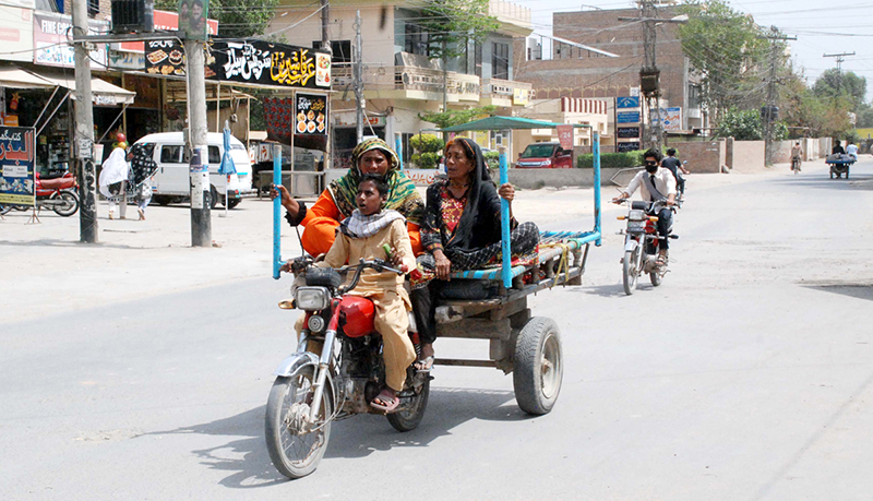 A family is traveling on a motor-cart driven by a boy