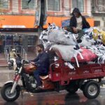 A tri-cycle rickshaw driver on his way loaded with heavy scrap bags at Nisbet Road