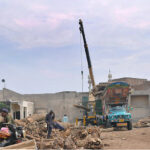 Laborers are busy loading heavy wooden pieces on truck with the help of a crane at Timber Market