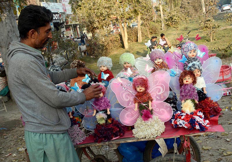 Vendor busy in arranging and displaying beautiful dolls to attract the customer at his roadside setup