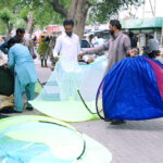 People buying mosquito nets for children from a roadside stall.