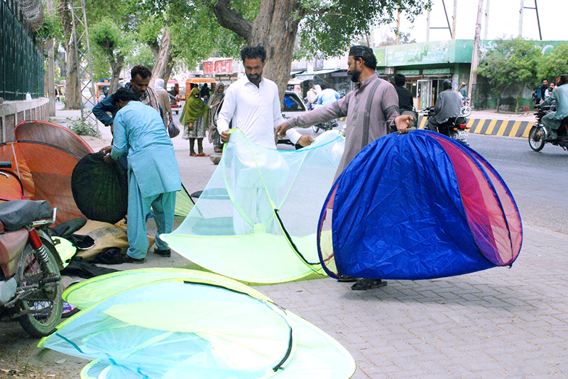 People buying mosquito nets for children from a roadside stall.