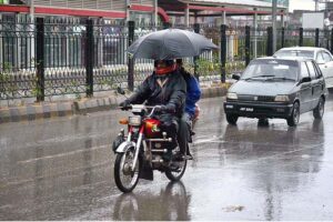 Motorcyclists on their way under the cover of an umbrella to protect from rain that experienced the Provincial Capital