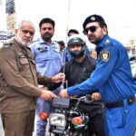 Traffic Police staffer installing free safety wires on motorcycles