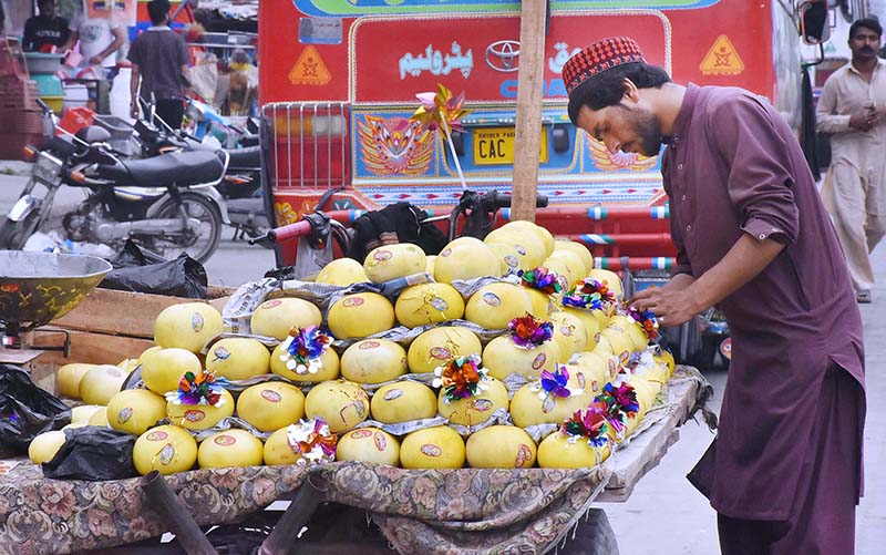 A vendor is decorating melons with flowers and stickers to attract customers