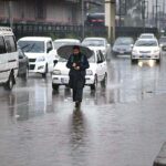 Motorcyclists on their way under the cover of an umbrella to protect from rain that experienced the Provincial Capital