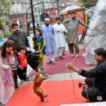 A juggler earning his livelihood by performing monkey tricks to entertain children