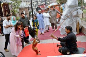 A juggler earning his livelihood by performing monkey tricks to entertain children