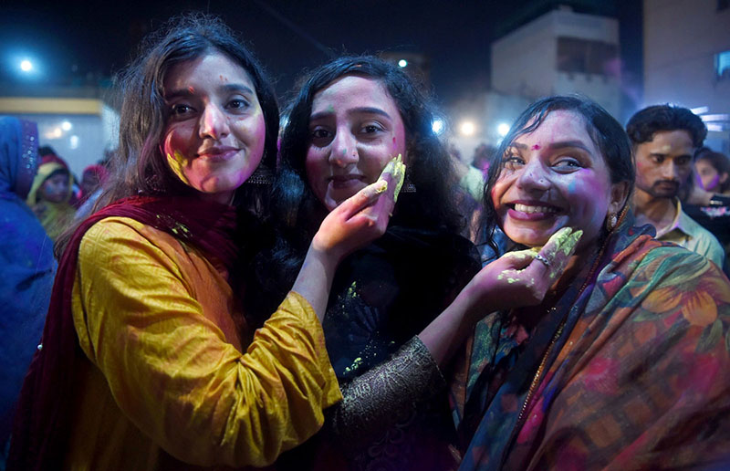 Hindu women devotees daubed in coloured powder take part in Holi celebrations at the Swaminarayan Temple.