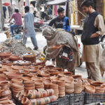 A woman is buying pottery from road side vendor