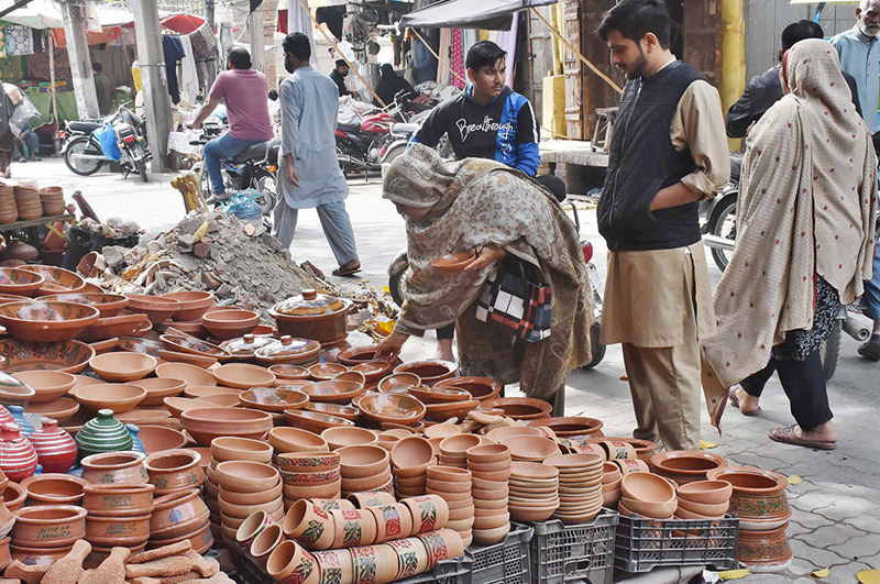 A woman is buying pottery from road side vendor