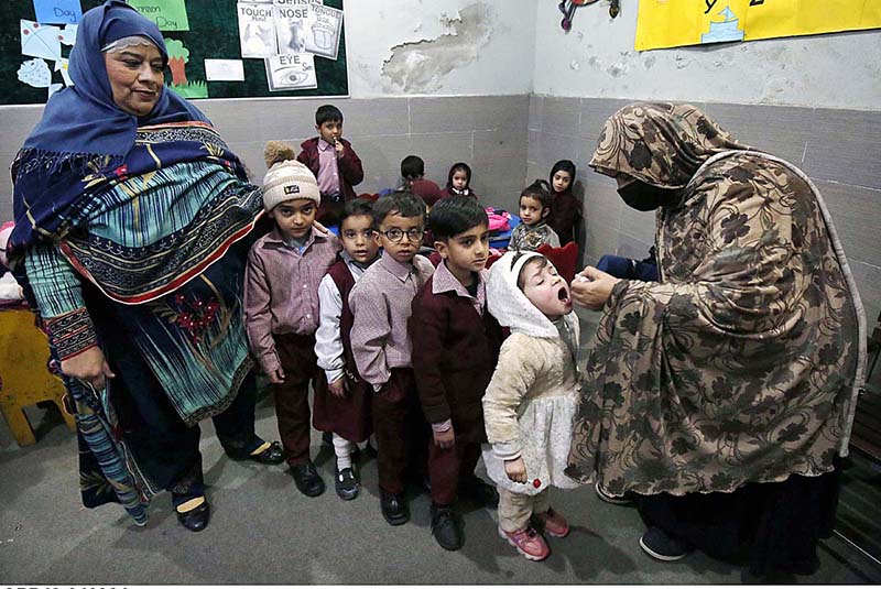 Polio worker administering polio drops to children at local school during anti-polio vaccination campaign in Provincial Capital