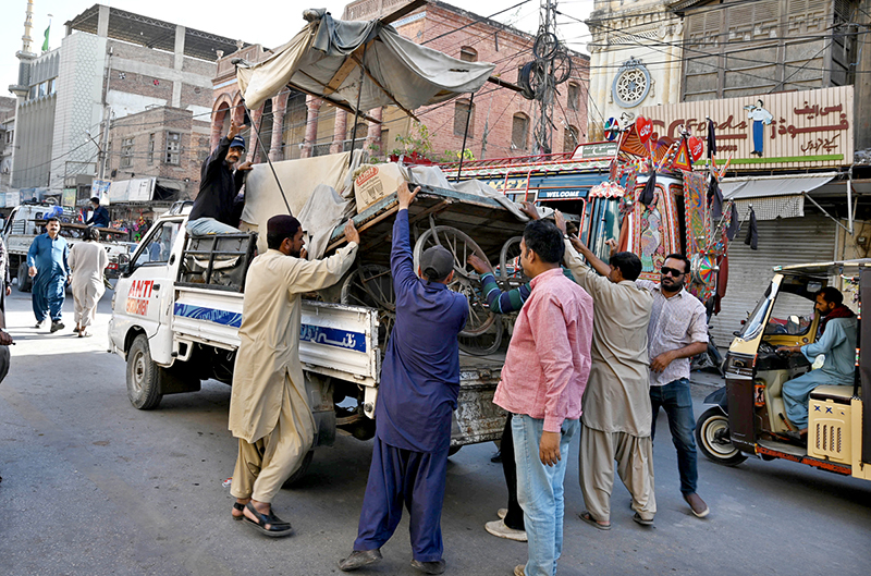 Anti-encroachment staffer loading roadside vendors handcart to their vehicle for clearing encroachments from Station Road.