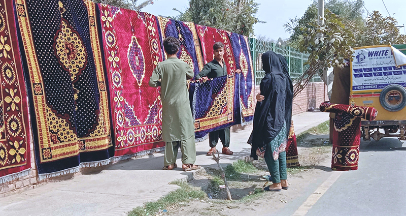 Some people buying machine woven carpets from roadside stall.