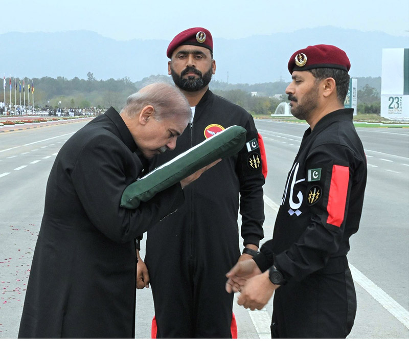 As a gesture of respect, Prime Minister Muhammad Shehbaz Sharif caress Pakistan flag presented to him by Major General Adil Rehmani of Special Services Group of Pak Army during Pakistan Day Parade 2024
