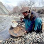 An aged man using traditional method to extract alluvial gold on the river bank