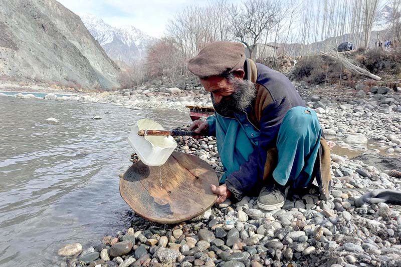 An aged man using traditional method to extract alluvial gold on the river bank