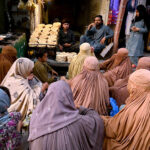 Women waiting in front of a Tandoor for free distribution of bread loaf by philanthropists at Ghanta Ghar Chowk