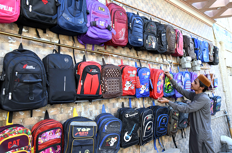 A vendor arranging and displaying school bags to attract the customers at Bakrani Road.