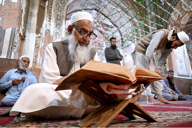 An aged man is reading the Holy Quran after Jumma Prayer at Masjid Muhabbat Khan.