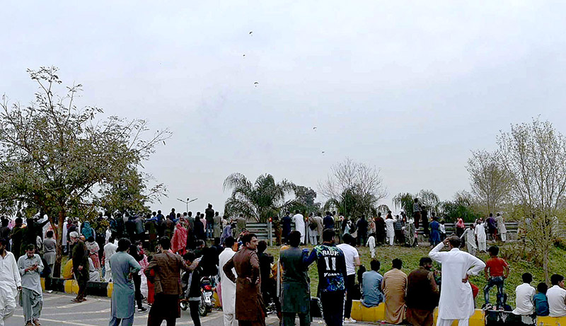 A large number of people watching the aircraft fly-past demonstration by Pakistan Air Force in Pakistan Day 2024 parade outside Shakarparian Parade Ground