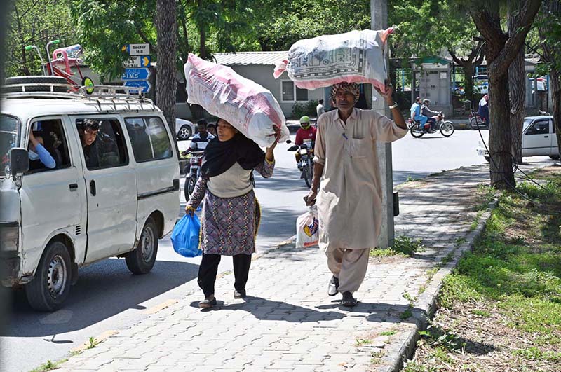 An elderly couple on the way carrying bags on their head in Federal Capital