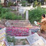 A woman reciting verses of Holy Quran on grave of her family member in graveyard on the occasion of Eidul Fitr