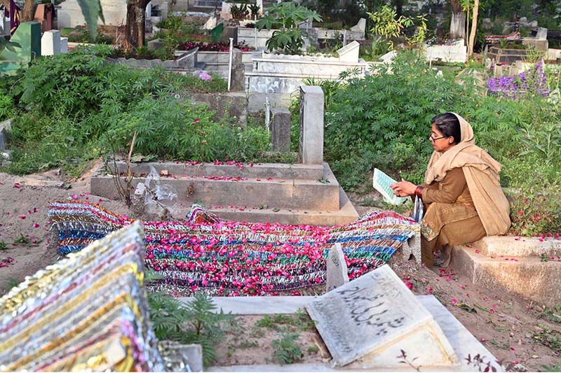 A woman reciting verses of Holy Quran on grave of her family member in graveyard on the occasion of Eidul Fitr
