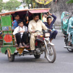An over loaded motor rickshaw book by a family in risky way traveling on a busy road