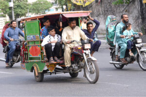 An over loaded motor rickshaw book by a family in risky way traveling on a busy road