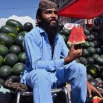 A vendor displaying and selling watermelon to customers at his roadside setup in Federal Capital