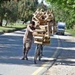 A vendor on the way along with his bicycle loaded with wooden stools for selling in Federal Capital.