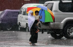 A motorcyclist on the way while cover himself with plastic sheet to protect from during rain that experienced the Twin Cities.