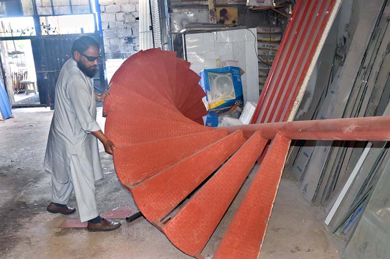 A worker busy in making iron stair at his workplace, IJP Road