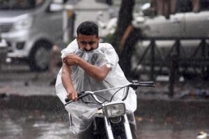 A motorcyclist on the way while cover himself with plastic sheet to protect from during rain that experienced the Twin Cities.