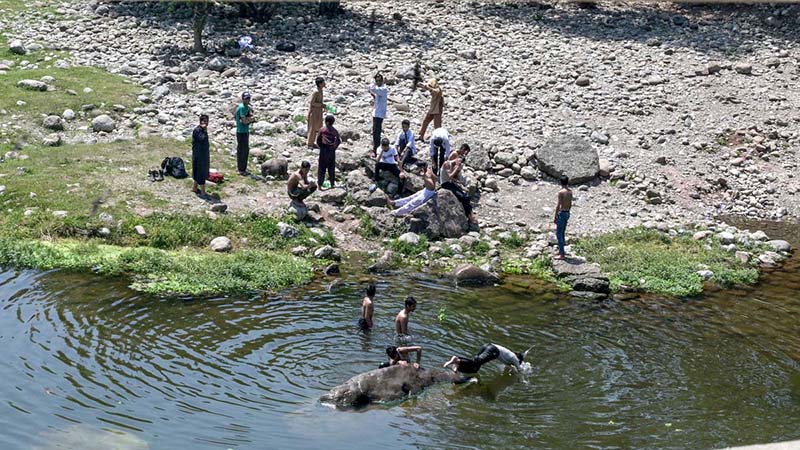 Youngsters bathing in Korang Nullah to get relief from hot weather in Federal Capital.