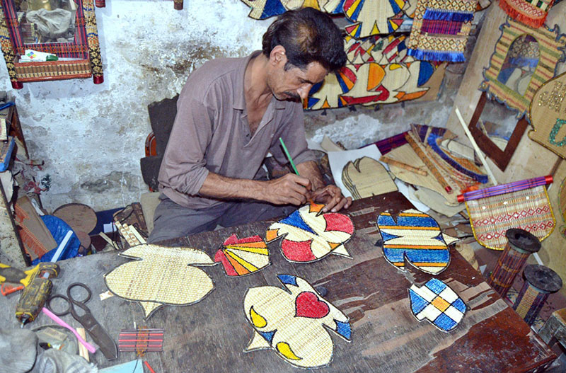 An artisan is giving final shape to various decorative artwork patterns at his work place.