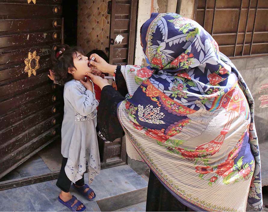 Lady Health Worker administering polio drops to a child during anti polio campaign at Dalazak Road.