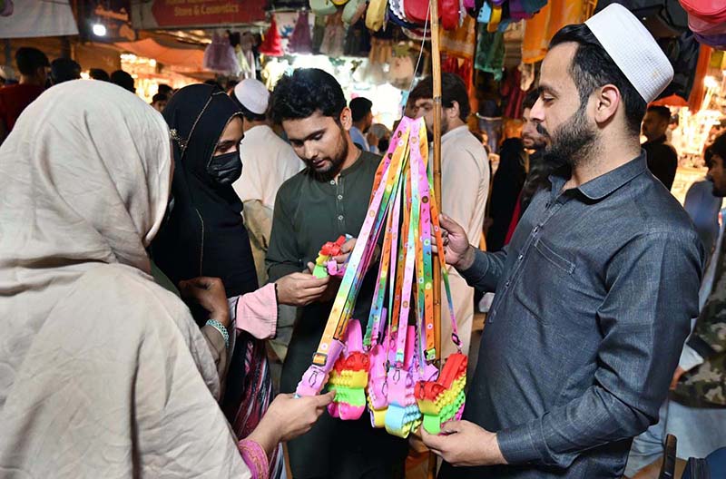 Customers selecting and purchasing children purse during Eid shopping at Gora Bazar.