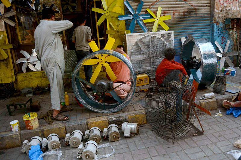 Electricians busy assembling big size exhaust fans at their workplace